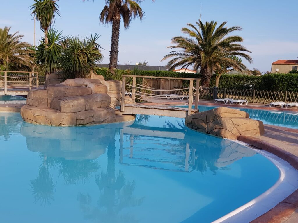 Aménagement de piscine avec décor roche et passerelle bois